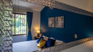 A bedroom with a bed, a nightstand, a lamp, and a window with curtains. - Poolside in Paradise: Walk to the Beach and More! (Coco)