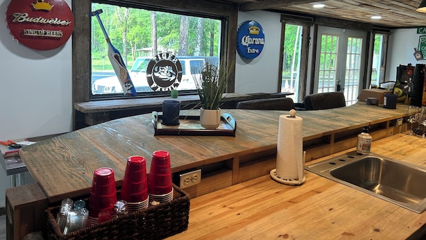 Een bar met een houten toonbank, een spoelbak en diverse baraccessoires.