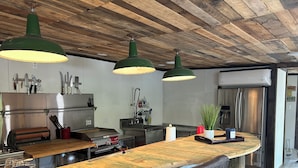 Een keuken met een houten plafond, een roestvrijstalen koelkast en een bargedeelte met krukken.
