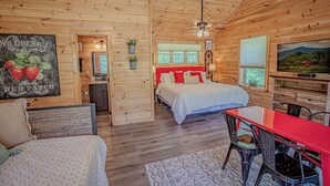 L’intérieur d’un chalet en bois comprend un lit, une table à manger et un téléviseur.