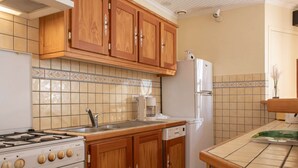 Una cucina con mobili in legno, un fornello, un frigorifero e una macchina per il caffè.