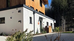 A modern two-story building with a white facade and wooden accents, surrounded by a cobblestone driveway and lush greenery. - Cozy Double Room - Private Entrance – Easy Self Check-In (Rum)