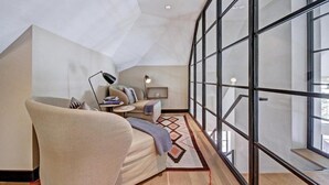 A modern interior with a high ceiling, a sofa, a small table with a lamp, and a large window offering a view. - Luxury 5BR Penthouse Residence at The Ritz-carlton Club Vail (Vail)