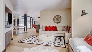 A modern living room with a white sofa, red and grey cushions, a white bean bag, and a geometric rug. - Luxury 5BR Penthouse Residence at The Ritz-carlton Club Vail (Vail)