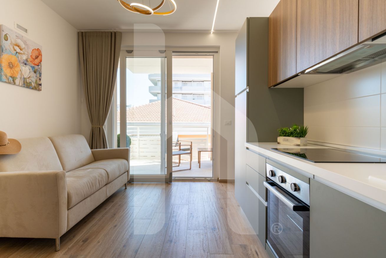 A modern kitchen with a built-in oven and a dining area with a sofa and a table.