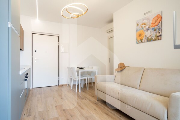 Un salon moderne avec un canapé beige, une table à manger avec des chaises et un tableau accroché au mur.