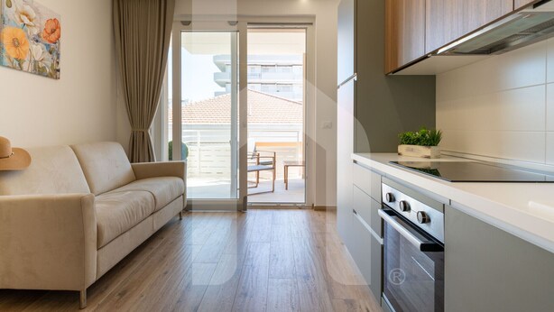A modern kitchen with a built-in oven and a dining area with a table and chairs. - Homiday - Residence Incanto - Mint (Alba Adriatica)