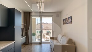 Ein modernes Wohnzimmer mit einer Couch, einem Essbereich mit Tisch und Stühlen sowie einer Küchenzeile mit Schränken und einer Arbeitsplatte.