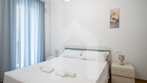 Ein Hotelzimmer mit einem Bett, zwei Nachttischen, einer Lampe auf jedem Tisch und einem Bild an der Wand.
