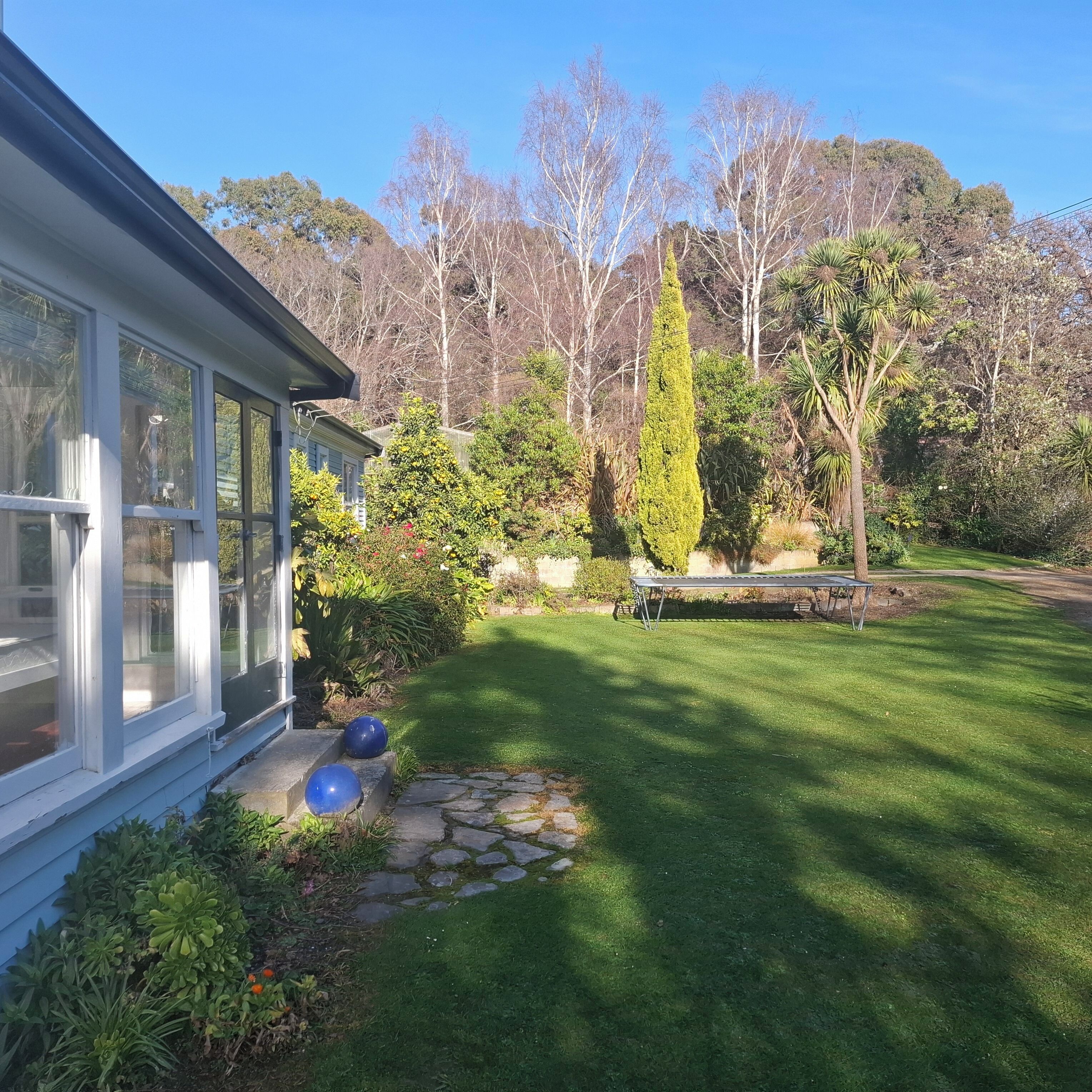 A house with a large glass window, a stone pathway, and a well-maintained lawn.
