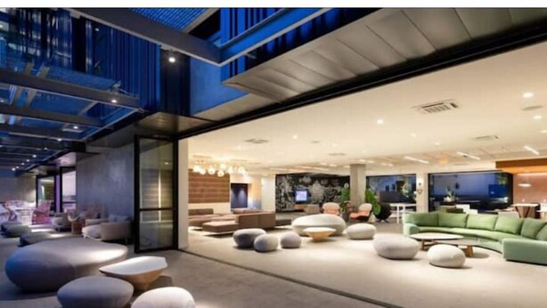 Un hall d’hôtel moderne doté d’un vaste espace salon, d’un grand téléviseur à écran plat et d’un design contemporain.
