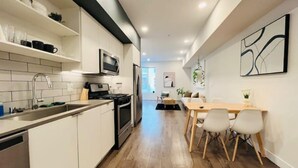 Une cuisine moderne avec des meubles blancs, un réfrigérateur en acier inoxydable et un four à micro-ondes.