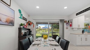 Un comedor con una mesa dispuesta para seis, un letrero de cafetería y vistas al exterior.