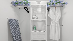 Un baño blanco con un perchero, una bata blanca y un estante con una botella verde.