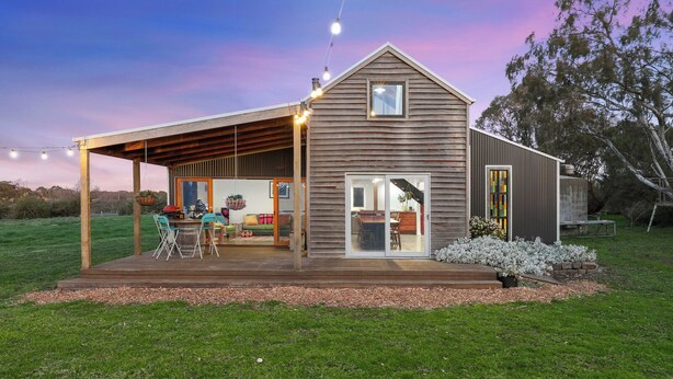 A modern house with a covered patio, a dining area, and a kitchen visible through glass doors. - Cozy cabin in peaceful Wangoom with AC, WiFi (Wangoom)