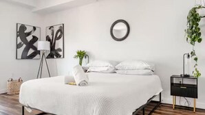 Ein modernes Schlafzimmer mit einem großen Bett, einem Nachttisch, einer Lampe und Wandbildern.