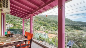 Un balcón con mesa y sillas, con vistas a un paisaje montañoso.