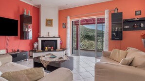 Un salón con chimenea, un sofá, una televisión y un balcón con vistas.