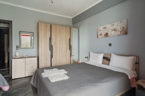 Un dormitorio con cama, armario, mesita de noche y un cuadro en la pared.