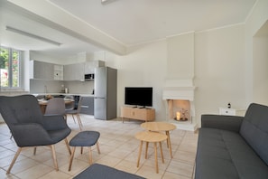 En moderne stue med sofa, stole, fjernsyn og pejs.