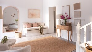 Ein minimalistisches Wohnzimmer mit einer Couch, einem Couchtisch, einem Teppich und einem Konsolentisch mit Dekoration.