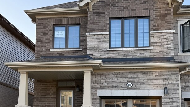 A two-story house with a garage, a front porch, and a well-maintained lawn.
