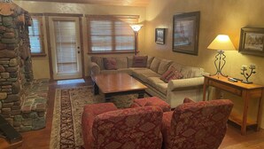 A cozy living room with a stone fireplace, a sofa set, a coffee table, and a lamp. - 3 BRD Apartment (Bigfork)