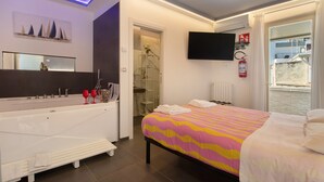 A modern hotel room with a large bed, a bathtub, a shower, a TV, and a balcony with a view. - Room 'Stella Marina' with Shared Terrace, Wi-Fi and Air Conditioning (Mola di Bari)