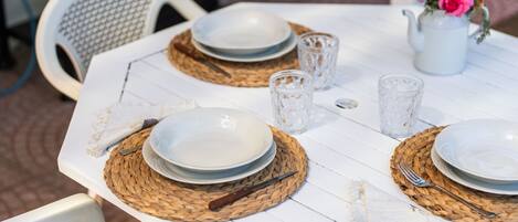 A table set with plates, cutlery, and a pitcher of flowers.