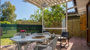 Un patio coperto con tavolo apparecchiato per mangiare, sedie e un lampadario.