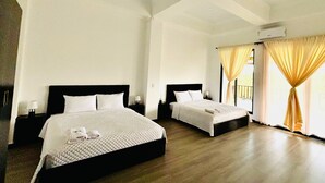 A hotel room with two beds, a wooden floor, and a large window with curtains. - HOTEL FINCA PROCEL (Palora)