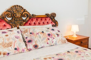 Una cama con una colcha estampada, un cabecero de madera y una mesita de noche con una lámpara.