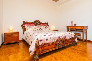Un dormitorio con una cama de madera, dos mesitas de noche, un tocador y una silla.