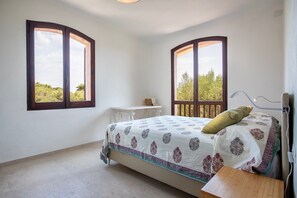 Una camera da letto con un letto, una scrivania e due finestre con vista.