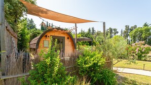 A wooden cabin with a curved roof, surrounded by lush greenery and a wooden fence. - Unique 'Prestige Barrel' Cottage with Private Pool, Wi-Fi, and Air Conditioning (Jonquières)