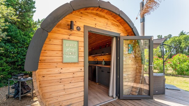 A wooden cabin with a glass door, a sign reading 'VIVEZ LIEU PENSEZ MOINES,' and a deck area. - Unique 'Prestige Barrel' Cottage with Private Pool, Wi-Fi, and Air Conditioning (Jonquières)