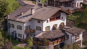 A multi-story building with balconies, a covered outdoor area, and a stone foundation. - Gasthof Kirchsteiger 'Zimmer 5' with Lake View, Shared Terrace and Wi-Fi (Santa Valburga)