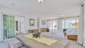 A spacious living area with a dining table, sofa set, and a bull figurine on a yellow mat.