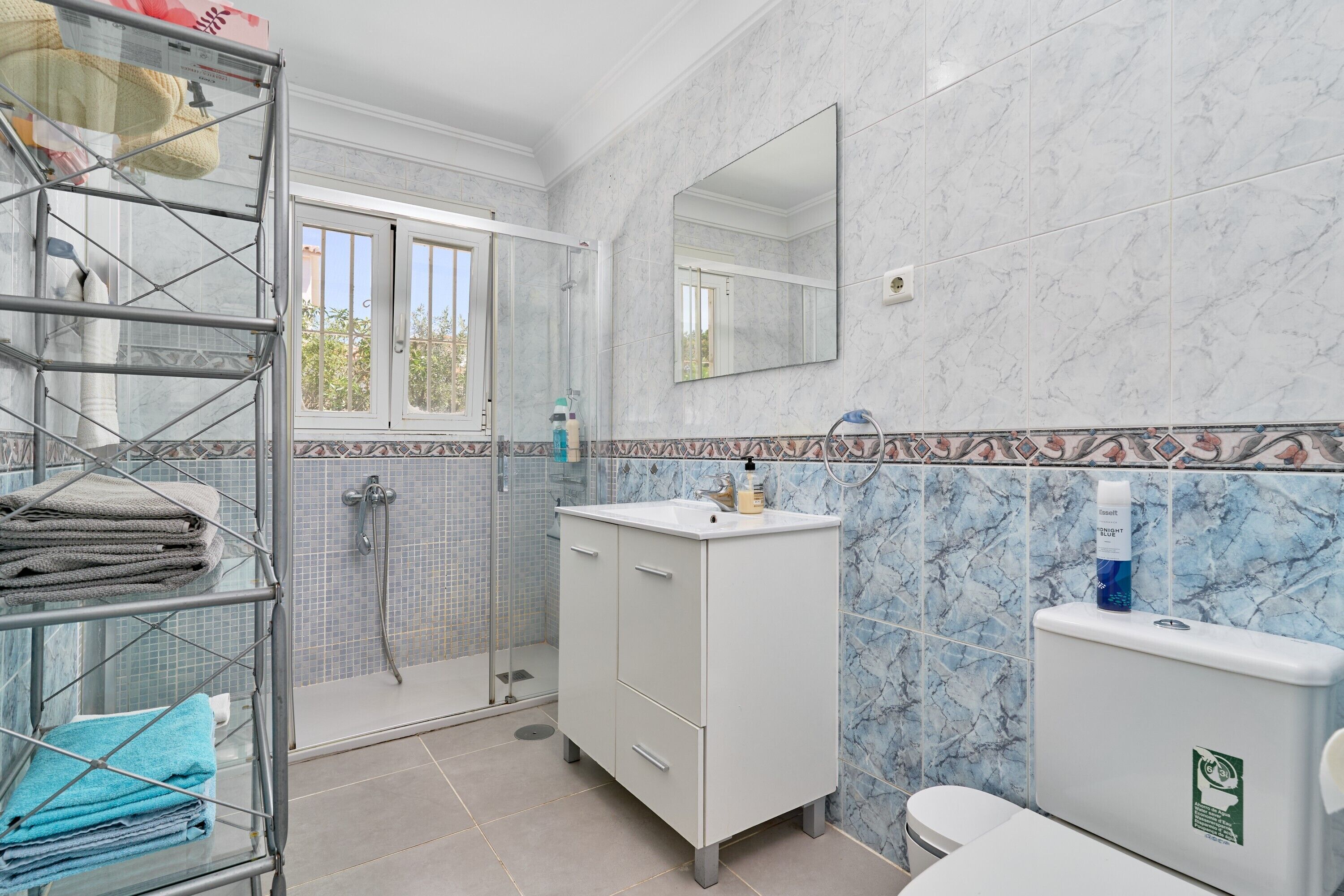 A bathroom with a shower, a sink, a toilet, and a towel rack.