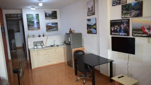 A compact kitchen with a dining area, a TV mounted on the wall, and several framed pictures depicting local scenes. - Central and Cozy Apartment (Tarapoto)