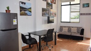 A modern kitchen with a refrigerator, a dining table with chairs, a sofa, and a TV mounted on the wall. - Central and Cozy Apartment (Tarapoto)