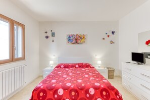 Ein Schlafzimmer mit einem Bett, Nachttischen, einem Fernseher und einem Fenster.
