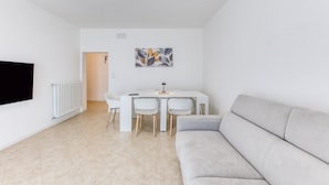 Una sala de estar moderna con un sofá, una mesa de comedor con sillas, un televisor de pantalla plana y un radiador.