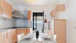 A modern kitchen with wooden cabinets, a gas stove, and a dining table set for four with plates and glasses. - Holiday Home 'Idrusa A Otranto' with Balcony, Wi-Fi and Air Conditioning (Otranto)