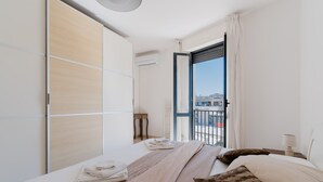 A hotel room with a bed, a large window, a balcony, and a wardrobe. - Holiday Home 'Idrusa A Otranto' with Balcony, Wi-Fi and Air Conditioning (Otranto)