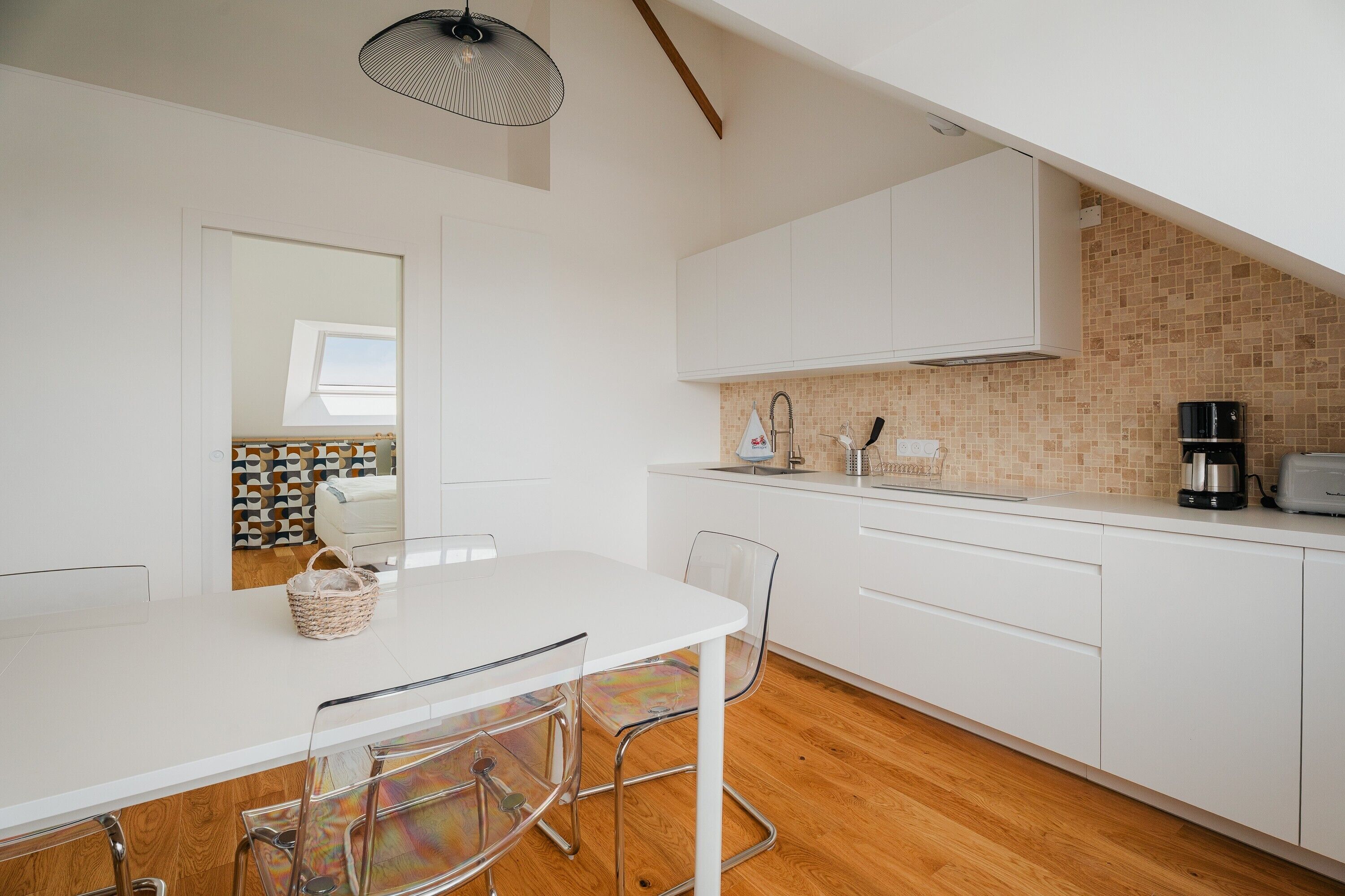 Una cucina moderna con mobili bianchi, pavimento in legno e un lucernario.