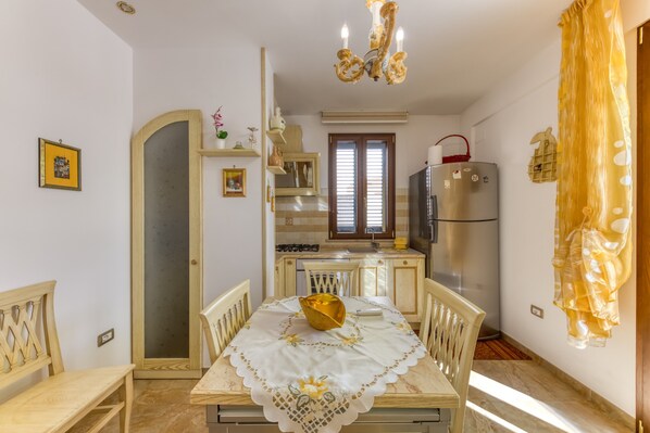 A dining area with a table set for two, a refrigerator, and a kitchen counter.