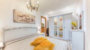 A bedroom with a bed, a chandelier, a wardrobe, and a mirror. - Apartment 'Filomena 1' with Private Terrace and Air Conditioning (Torre Vado)