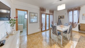 Un espace repas comprenant une table, des chaises, un vase avec des fleurs, un miroir et un luminaire au plafond.