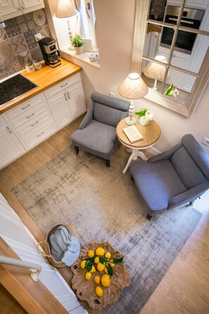 A modern kitchen with white cabinets, a coffee maker, and a dining area with two grey chairs and a small table. - Holiday Home 'Lianelia Boutique' with Wi-Fi and Air Conditioning (Argyrádes)